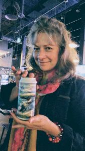 Irene Duma poses with a can of Quidi Vide beer which features her painting on the label.