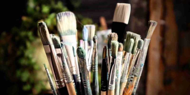 an assortment of oil painting brushes in a tin