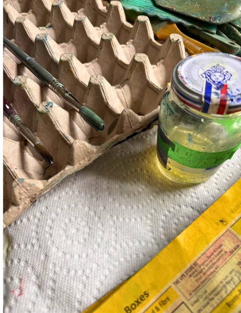 this is an image of oil paint brushes laid out on a brush holder which is just an egg crate.